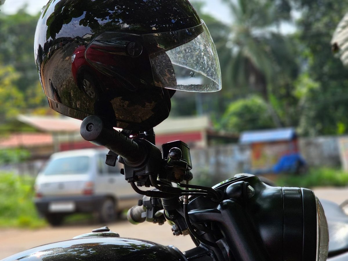 A helmet resting on the handlebar of a motorcycle parked by a South Indian road