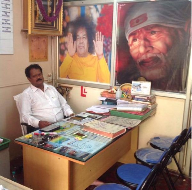 The proprietor of Prathibha Driving School at his desk in the office, with licence paperwork laid out