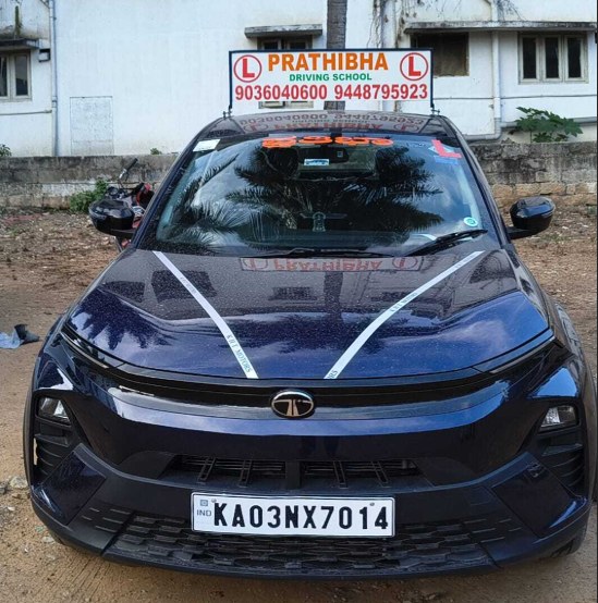 A Tata Nexon training car with Prathibha Driving School L-boards on the roof